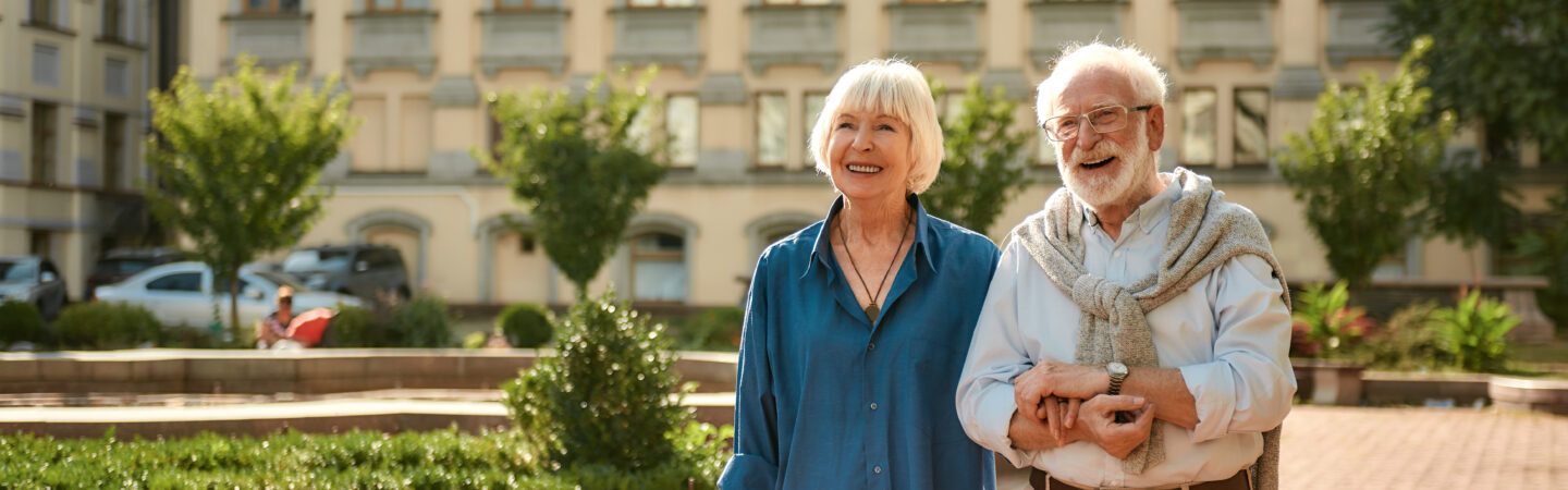 Active older couple holding hands and walking outdoors, reflecting a healthy lifestyle supported by pneumococcal vaccination